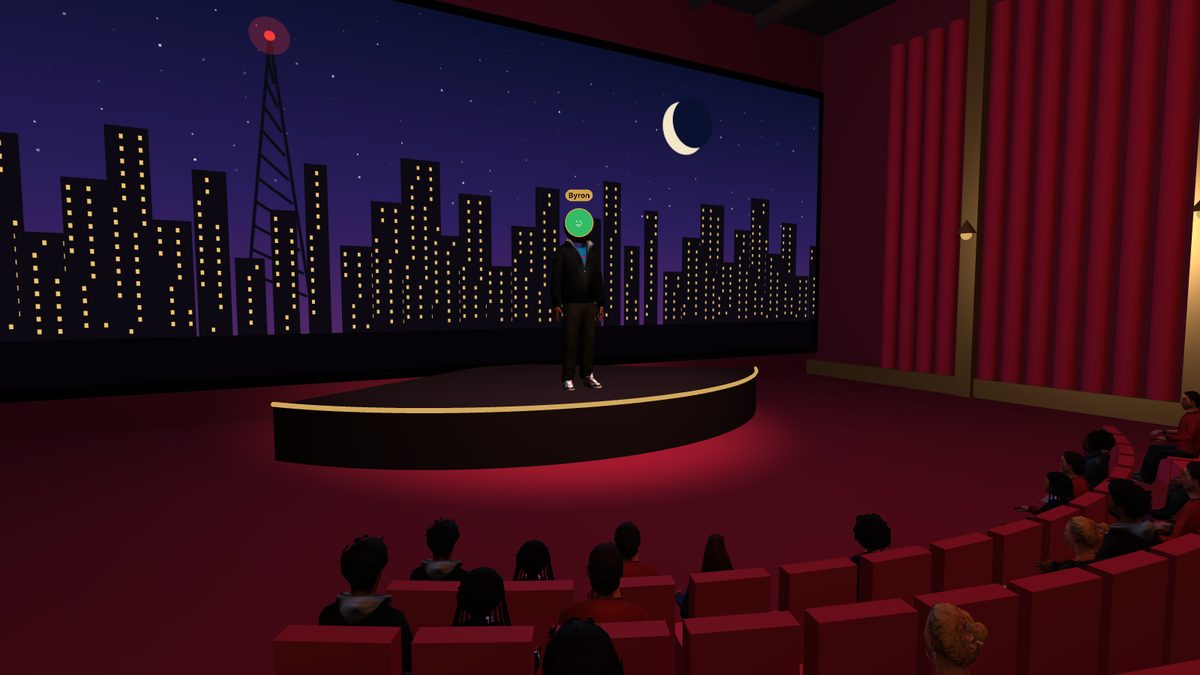 The admin on stage in front of the screen, with the audience watching
